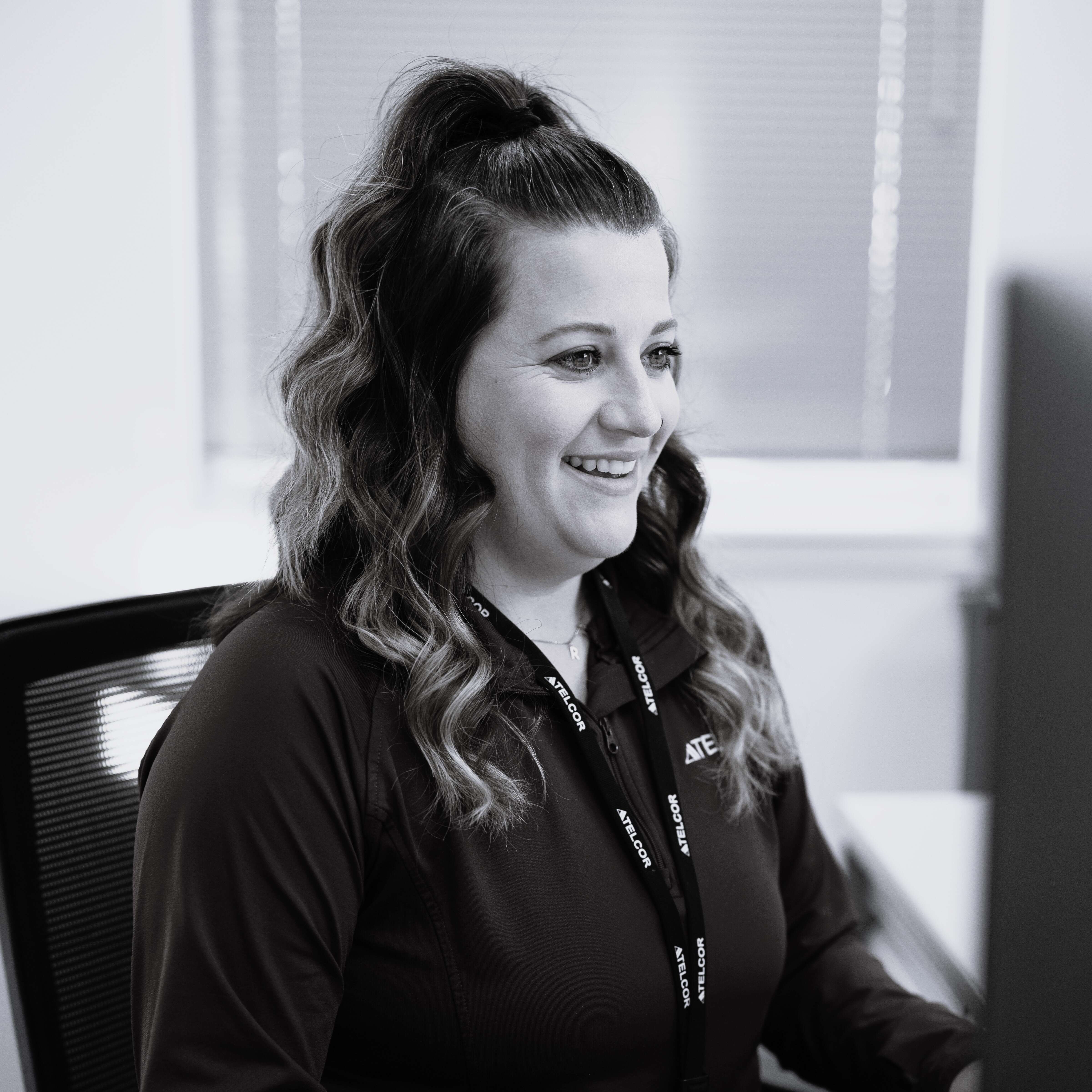 TELCOR employee smiling at computer monitor