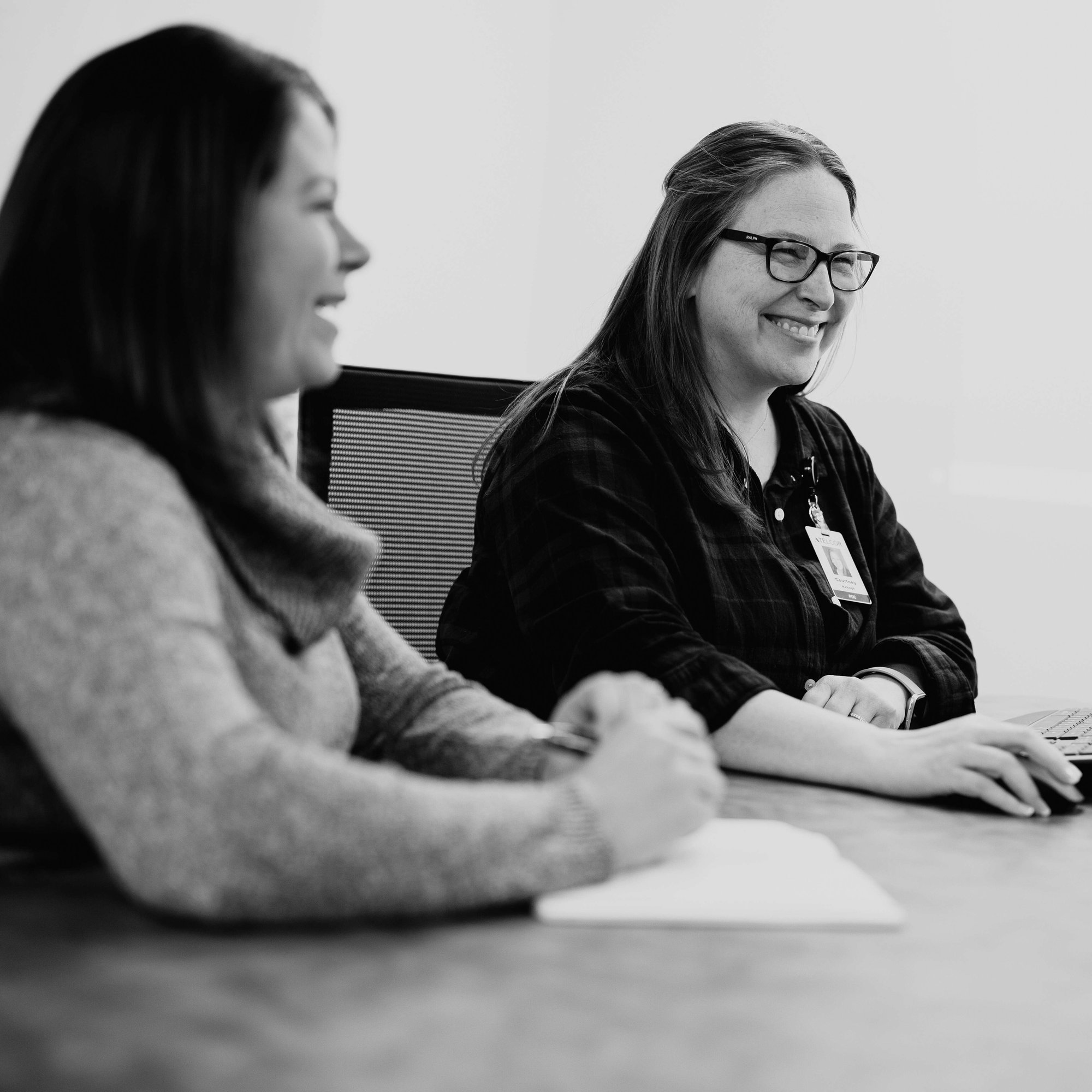 women sitting in conference room  smiling and talking