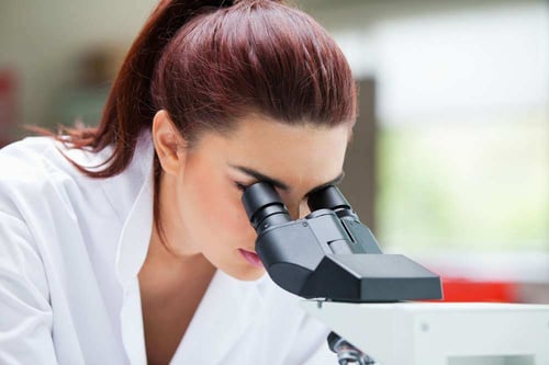 Close up of a scientist looking into a microscope in a laboratory